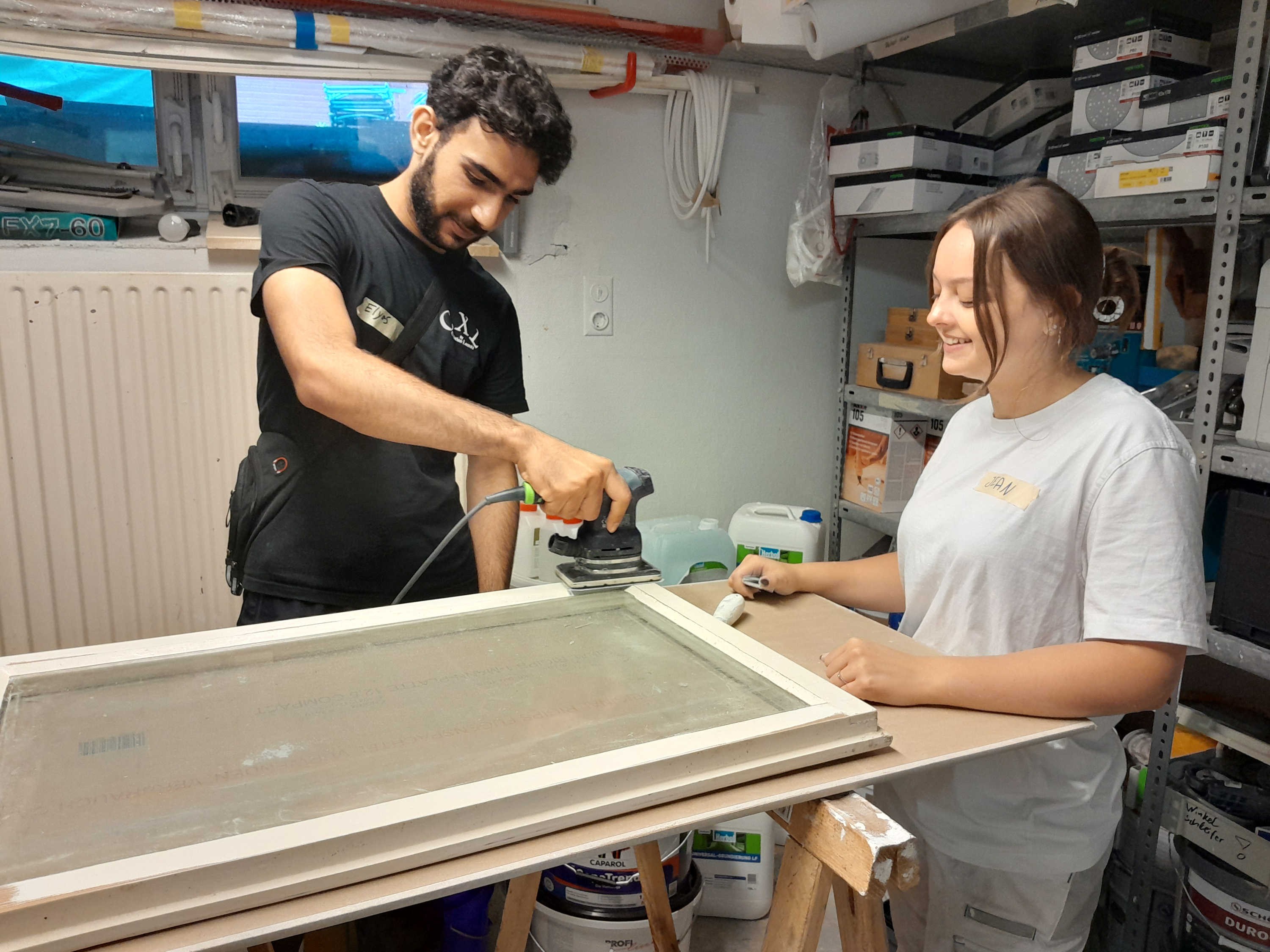 Auszubildende und Praktikant schleifen ein Fenster