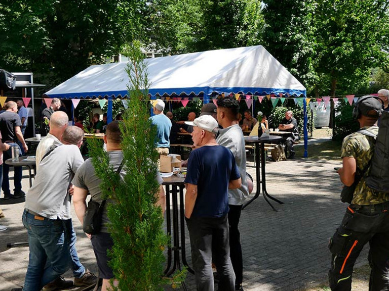 Menschen an Stehtischen im Hof Menschen an Stehtischen im Hof