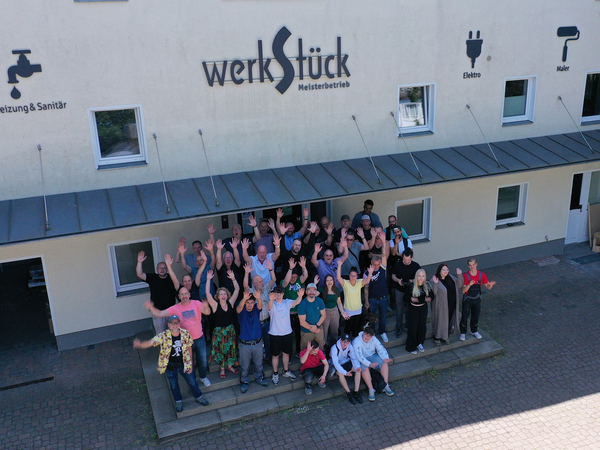Mitarbeitende stehen vor Gebäude von Werkstück Raumgestaltung & Versorgungstechnik GmbH - Bau und Handwerk Berlin