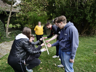 Gruppe Auszubildender und Personalentwicklerin Andrea Bogdan bei einer Teamübung mit einem Holzstück im Freien beim Azubi-Tag von Werkstück