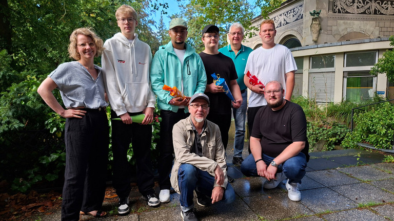 Gruppenbild der neuen Auszubildenden bei Werkstück mit Geschäftsführer und Mitarbeitenden auf der Terrasse der Wannse-Villa
